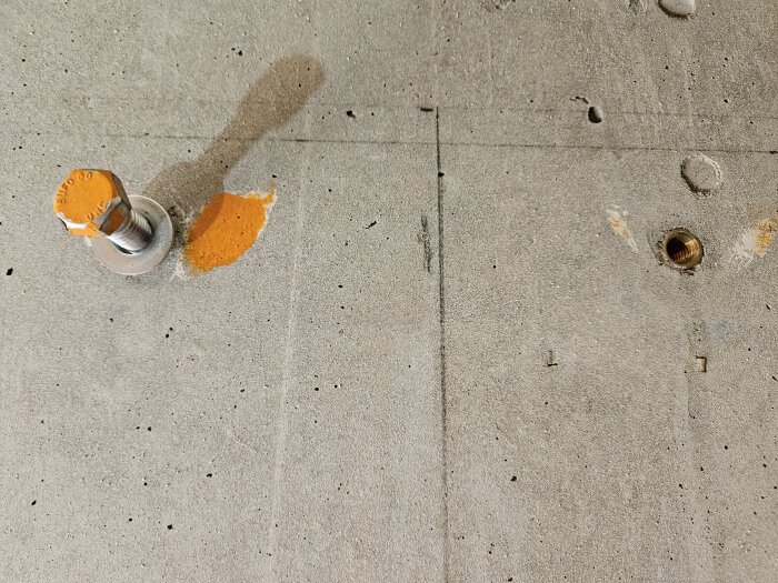 Bult med orange markering och borrhål i betongvägg.
