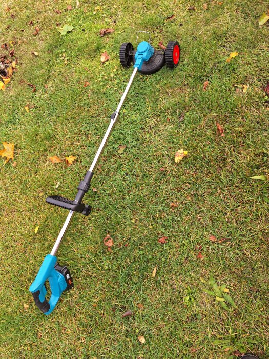Trimmer med hjul på gräsmatta, klar för användning.