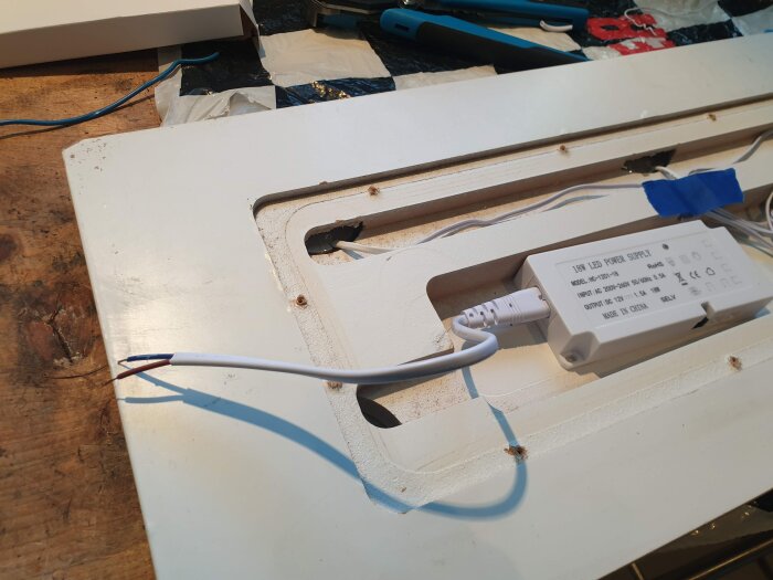 LED-drivdon monterat på en träpanel med synliga sladdar i förgrunden, verktyg och material i bakgrunden.