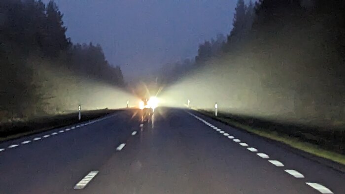 Möte med bil på landsväg i mörker, helljus bländar och gör vägkanterna svåra att se.