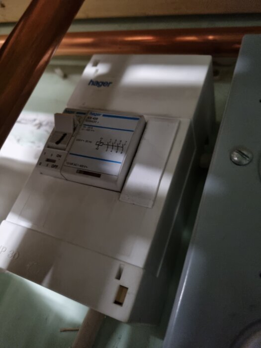 En jordfelsbrytare från Hager monterad vid kopparrör, diskussion om surrande ljud bakom bergvärmepump.