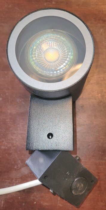 Svart spotlight på träbord, del av 12 stycken 7 watt lampor för trädgårdspåle med anslutning för trädgårdsverktyg och eventuellt trefasuttag.