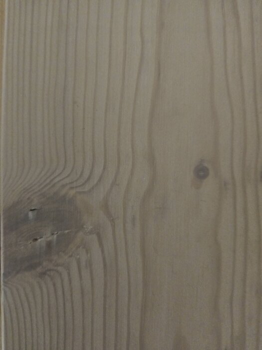 Massivt furugolv med synliga sprickor och ytbehandlingssläpp vid kvistar.