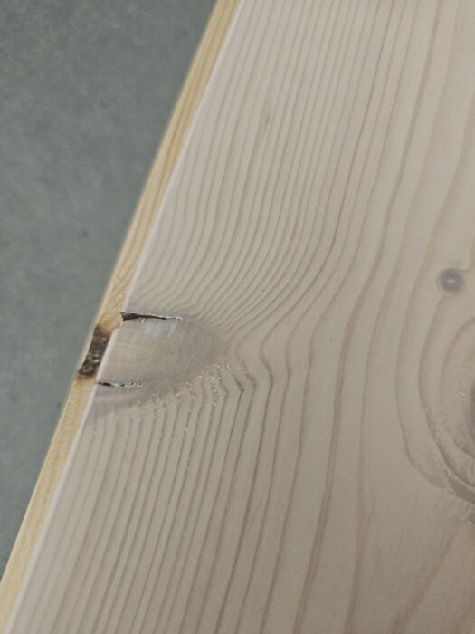 Massivt furugolv från Dalafloda med sprickor i kvistar och ytbehandling som släpper, visar problem med golvkvalitet.