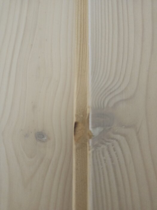 Massivt furugolv med sprickor i kvist och släppt ytbehandling.