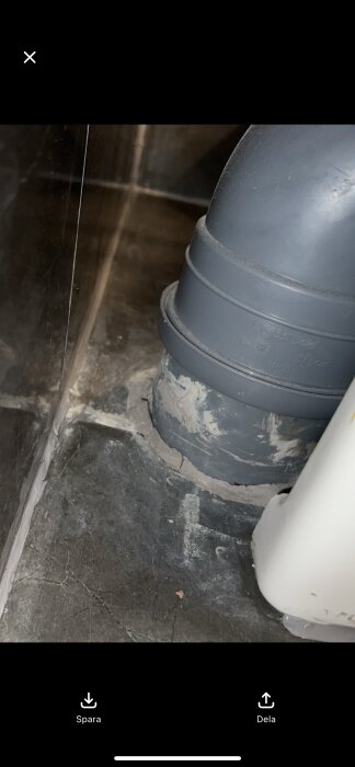 Avloppsrör från toalett, synligt med en spricka i tätningen vid golvet, som visar tecken på fukt från nyligen genomförd badrumsrenovering.