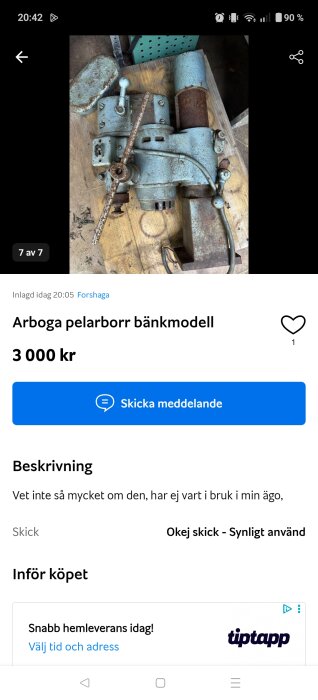 Arboga pelarborr bänkmodell, blå och rostig, demonterad, liggande på träyta, med manual växellåda och motor synliga.