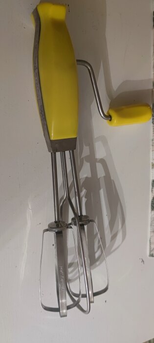 Gul och silverfärgad handvisp av äldre modell med mekaniskt vevhandtag, köpt på loppis.