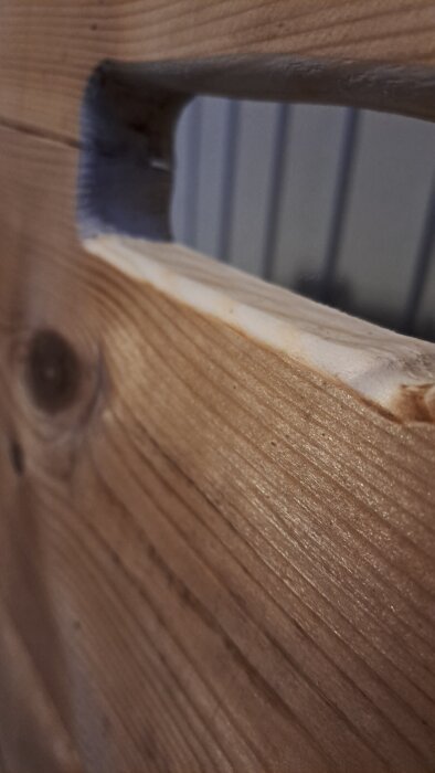 Ett närbildsfoto av ett nyfräst lyfthål i en trälucka, med träets ådring och kanter tydligt synliga.