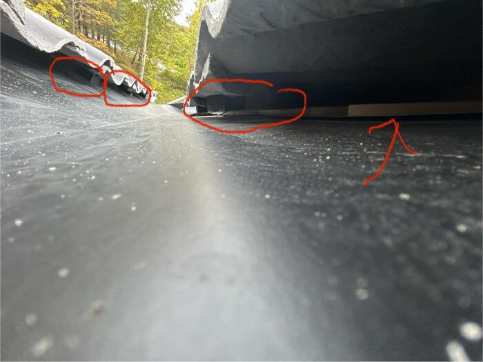 Närbild av tak med takpannor och ränndalsplåt, ströläkt ovan ränndalen synlig. Röda markeringar visar problemområden.