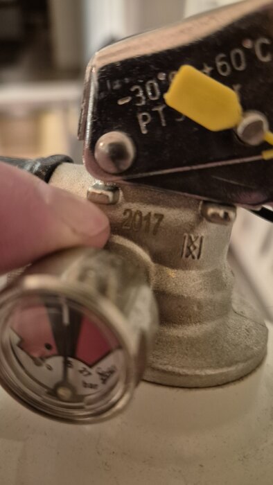 Närbild på en metallventil med en tryckmätare och temperaturangivelser samt siffermarkeringen "2917".