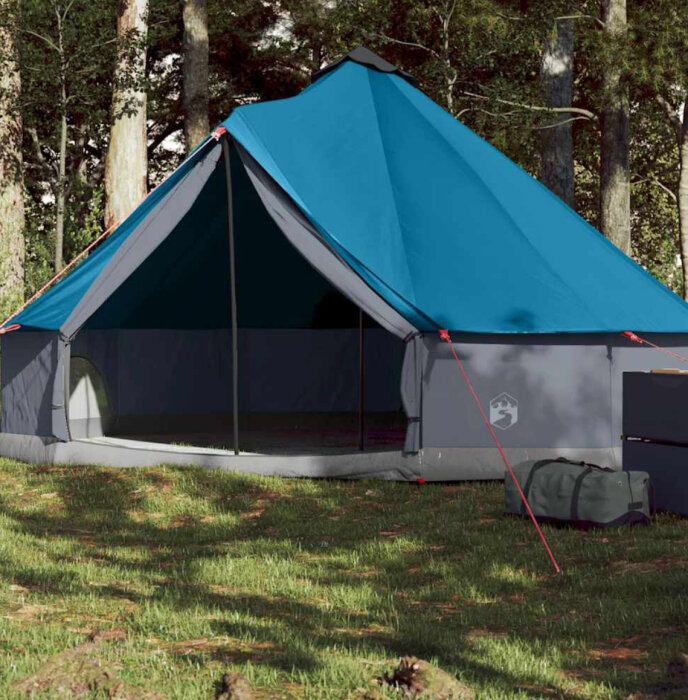 Blått tält med öppet stängt ute i grönskande skogsmiljö, uppställt på gräs med equipment bredvid.