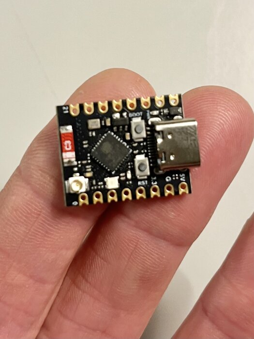 En liten mikrocontroller på ett kretskort som hålls mellan fingrarna.