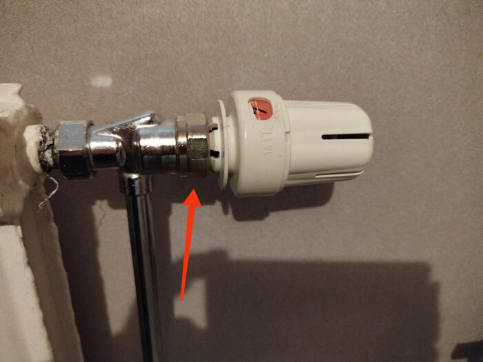 Termostat monterad på värmerör med röd pil som pekar mot fästpunkt för att lösgöra termostaten.