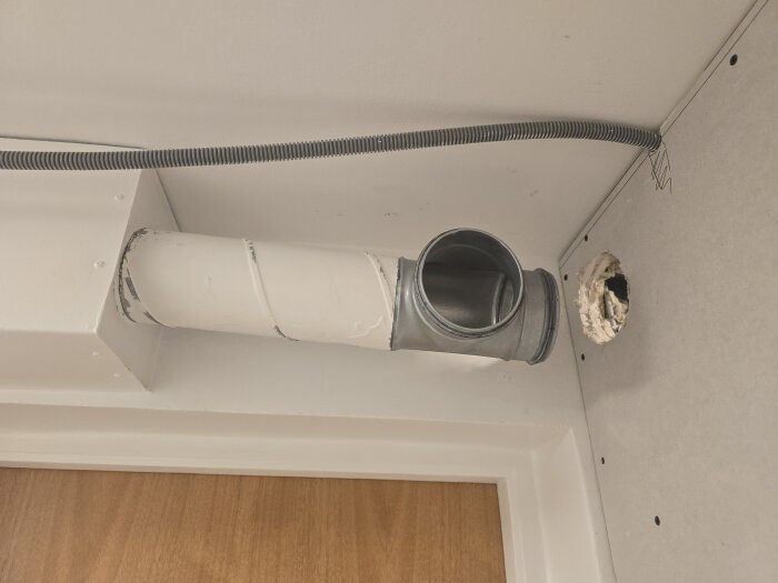 Ventilationsrör och flexrör monterade i klädkammaren, med hål i väggen för nätverkskabeldragning.