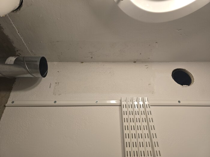 Ventilationsrör och en vägg med hål för framtida nätverksdragning, synliga flexrör och kabelkanaler i ett renoveringsprojekt.