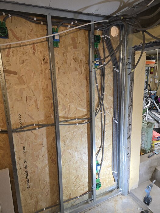 Installation av flexrör för CAT6-kablar på en OSB-skiva, med rörfördelning och metalldetaljer inför installation av nätverk i källarprojekt.