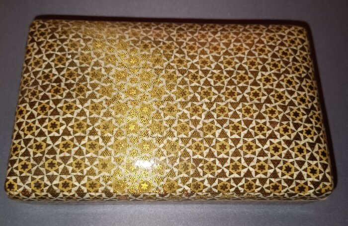 Dekorerad ask med intarsiakonst Khatam-kari, visande intrikata geometriska mönster i guld och brunt, typisk för hantverk från Isfahan, Iran.