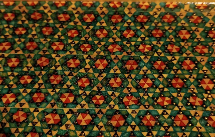 Intrikat intarsiamönster i traditionell Khatam-kari-stil, använd på en ask från Iran, med färger av grönt, rött och guld.