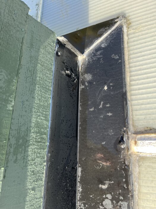 Läckande hörn vid tillbyggnad med plåt och panel, tätat med silikon.