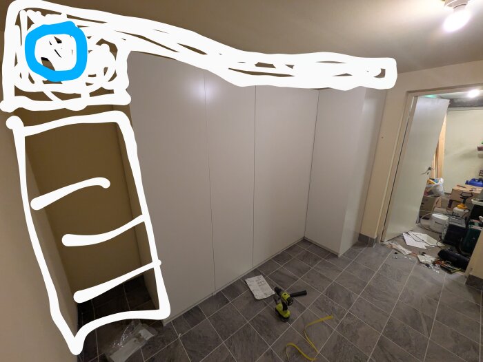 En vit IKEA Pax-garderob i en tvättstuga med en markerad hörna för tilluftsventil ovanför garderoben. Verktyg och bruksanvisningar på golvet.