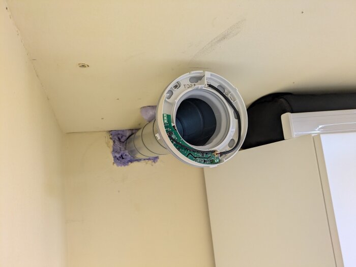 Ventilinstallation i en tvättstuga, monterad i hörnet av taket bredvid en Ikea Pax-garderob.