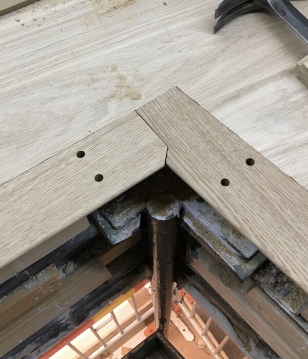 Vinkelmontering av träpanel över en stålpelare, del av ett spaljéprojekt. Skruvhål förborrade för monteringsdetaljer.