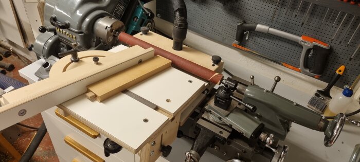 Svarv med inbyggd jig och sliprulle, verktyg hänger på väggen i bakgrunden.