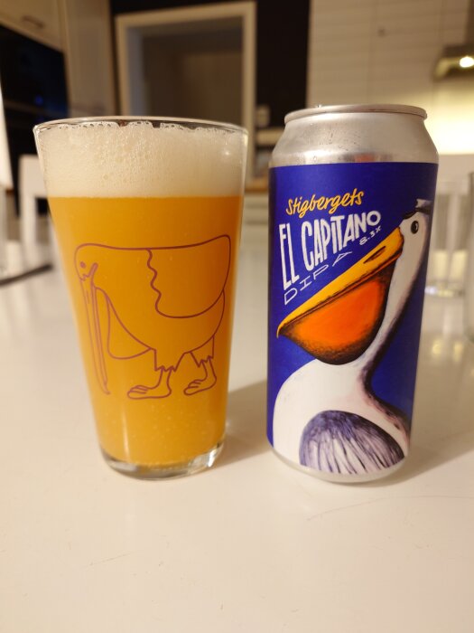 Glas med öl och burk med etiketten "Stigbergets El Capitano DIPA" på ett bord i ett kök.