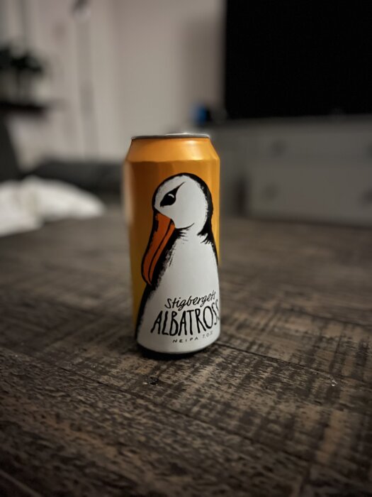 Orange burk med illustration av en albatross och texten "Stigbergets Albatross" placerad på ett rustikt bord.
