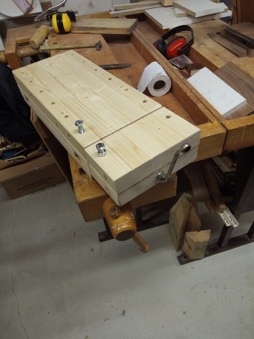 En nästan färdigbyggd mini-hyvelbänk i en verkstad, omgiven av verktyg och träbitar.