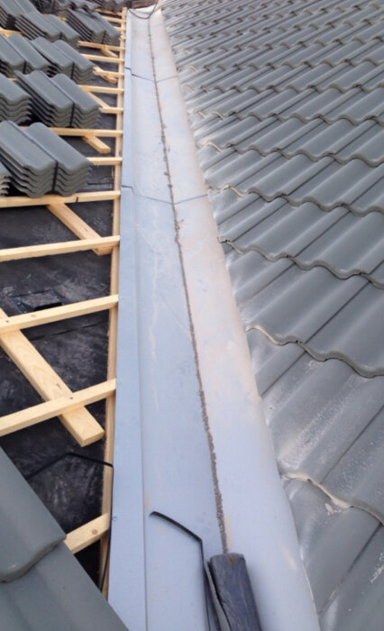 Ränndal på tak, byggt med grå takpannor och träkonstruktion, visar vanligt västkustutförande utan att följa AMA-standard, men är godkänd.