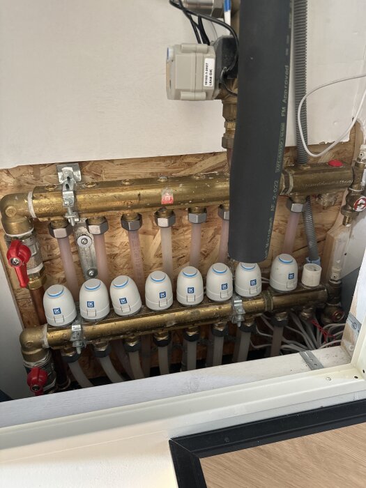 En golvvärmefördelare med flera vita reglerventiler där slinga nummer 4 har problem med att spola igenom vatten.