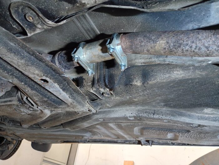 Monterat avgassystem under en Volvo, synligt är en skarvmuff fäst med klämmor där en ovanlig reparation tidigare gjorts.