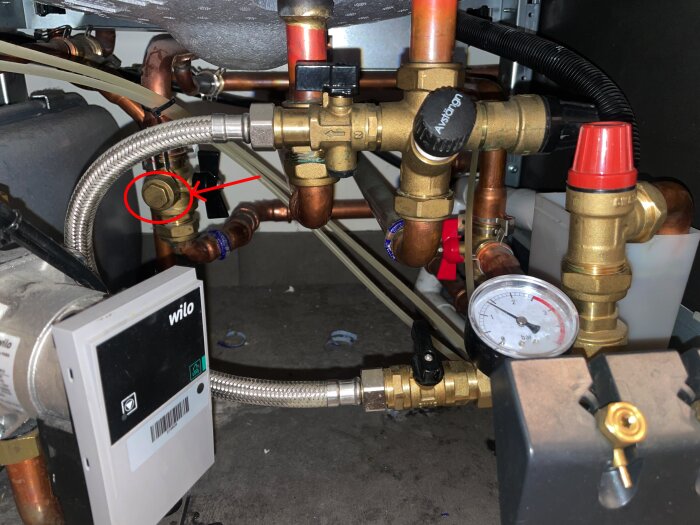 VVS-system med tryckmätare, ventiler och kopparrör. En röd cirkel markerar en specifik ventil.