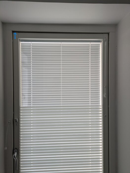 Balkongdörr med glapp i övre vänstra hörnet där dörren möter karmen, visad med blå pil för att ange riktning för justering.