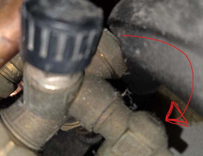 Äldre LK vinkelventil utan vred, nära fotad, med fokus på kopplingar och röret. En röd pil pekar från ventilen till objektet bredvid.