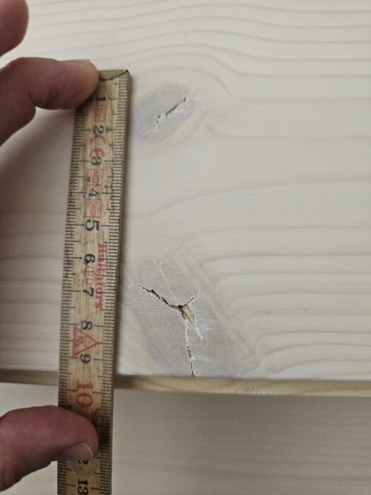 En träbit med spricka mäts med tumstock.