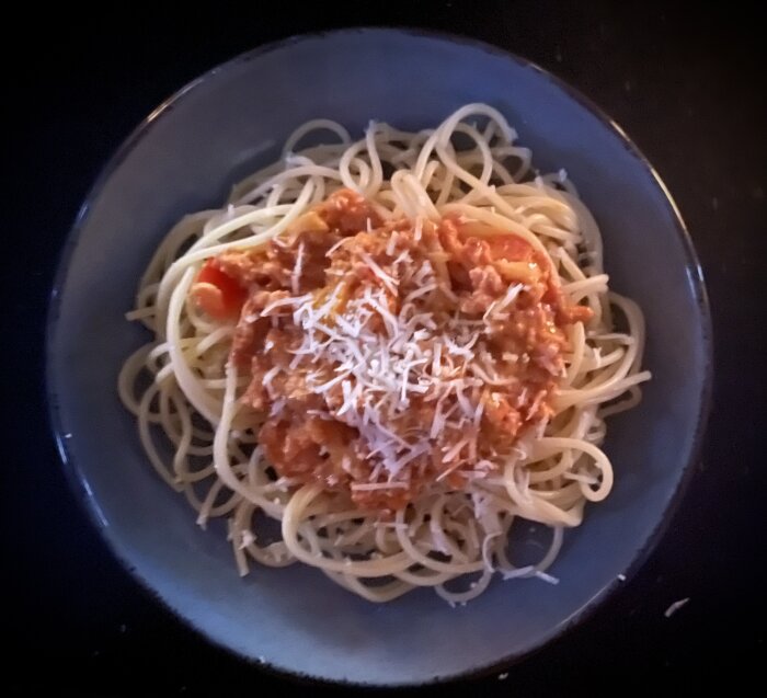 Tallerken med spaghetti toppad med salsicciafärs och riven ost.