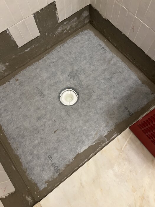 Golv med nytt tätskikt och avloppsbrunn under badrumsrenovering, med fokus på skarv i hörn och tröskelarbete.