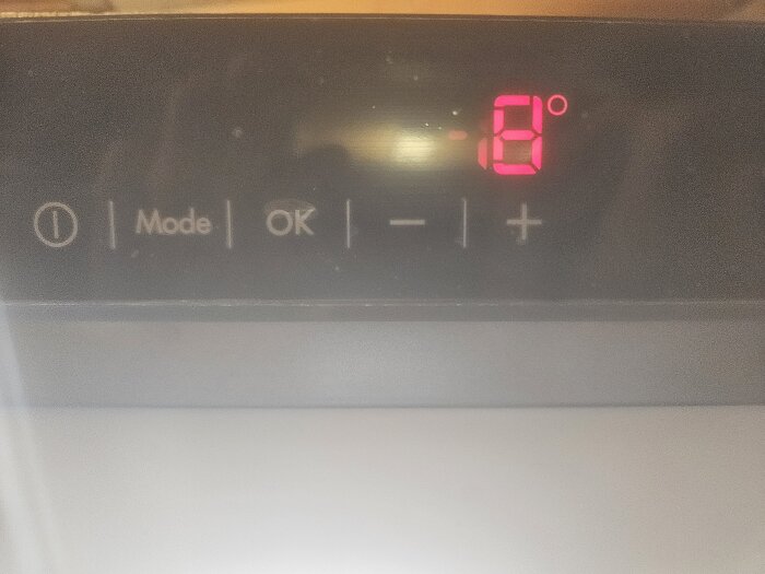Husqvarna frys display med temperaturinställning på minus 8 grader, mode-knapp och varningstriangeln intill.