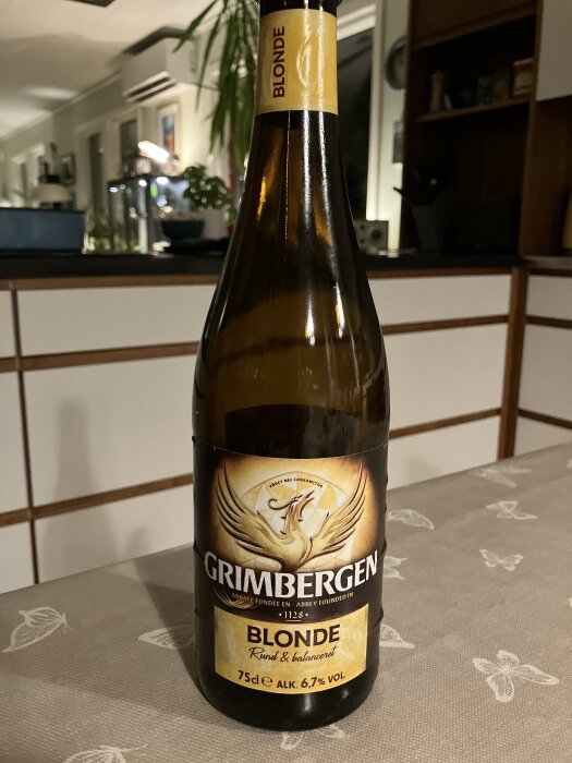 Flaska Grimbergen Blond öl på ett bord, 75 cl, 6,7% alkohol.