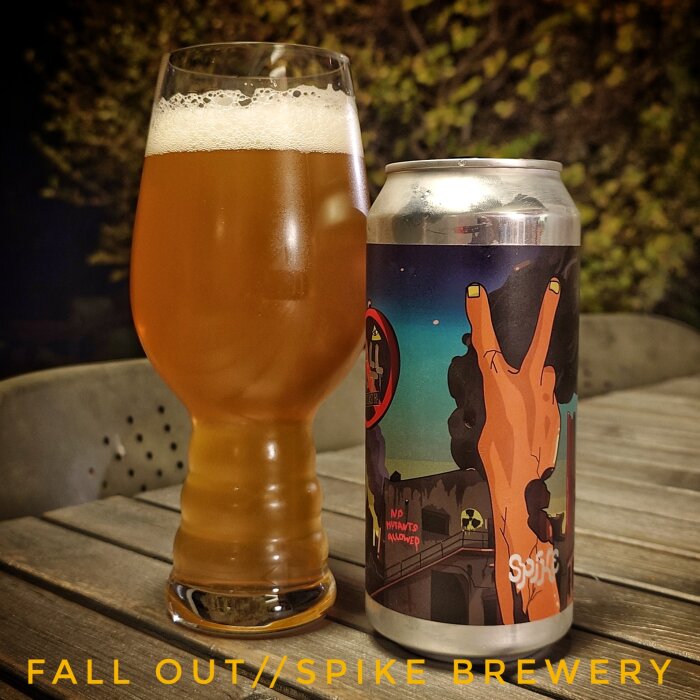 En öl från Spike Brewery bredvid ett glas öl på ett bord. Etiketten visar en tecknad hand som gör fredstecknet.