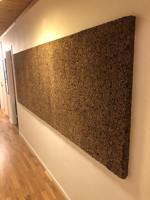 Korkmatta på vägg i korridor, monterad för potentiell ljuddämpning eller estetisk effekt i en källare från 60-talet.