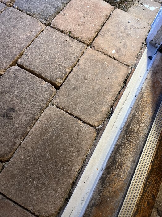 Ytterdörrens tröskel med intilliggande stenlagt steg som ska bytas ut mot trall.