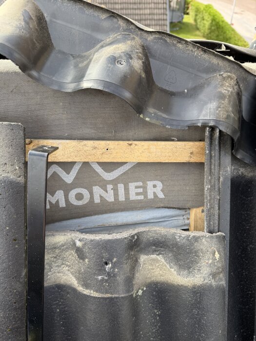 Närbild på takpannor och undertak, med en del av läkten synlig under pannorna. Taktegel är borttaget för att avslöja strukturen under.