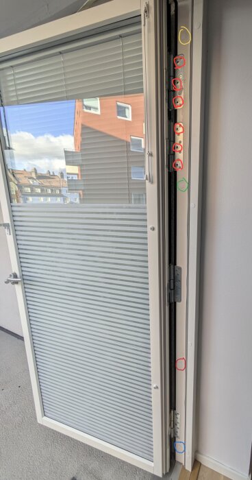 Gångjärn på dörr, skruvar markerade med färgade ringar. Fråga om justering av skruvarna.