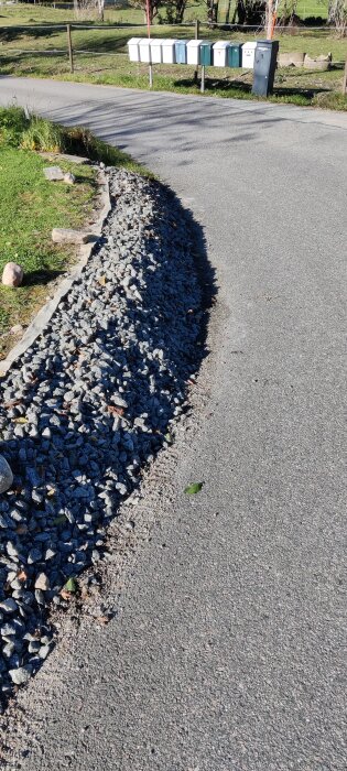Grus längs vägkanten vid en asfalterad väg, med postlådor synliga i bakgrunden.