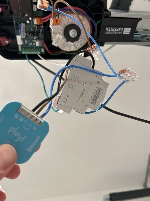 Elektrisk installation av garageportöppnare med synliga kablar och kopplingar.