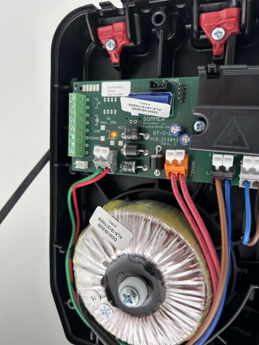 Elektronikkort och transformator med kopplade kablar i ett plastskal.